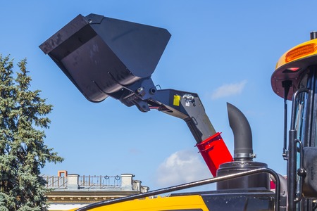 Raised bucket of an excavator over blue skyの写真素材