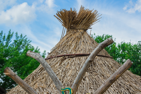 Old rural hut with a thatched roof made of straw. blue skyの写真素材