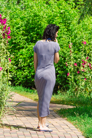 A sexy girl in a tight sea dress, walking along a stone path, a back view. summerの写真素材