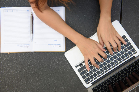 Woman working on laptop and writing, top viewの写真素材