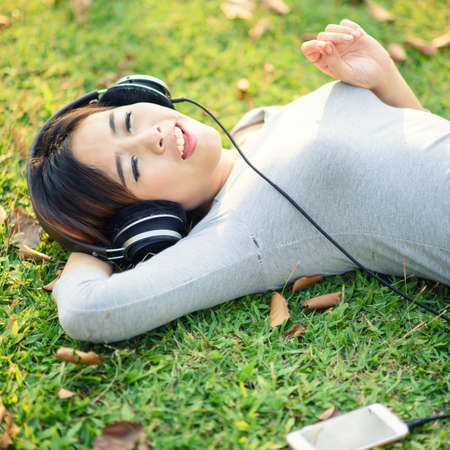 Young girl listening to music with headphone in city parkの写真素材