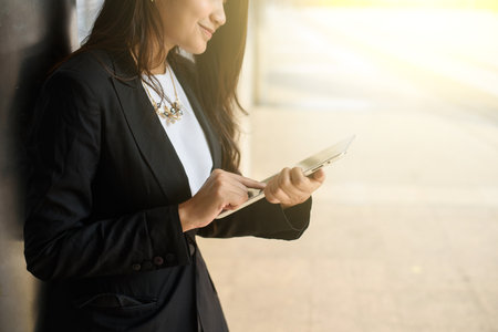 businesswoman in smart casual using digital tablet outdoorsの写真素材