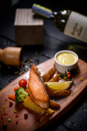 Salmon steak fried with vegetables on wooden tableの写真素材