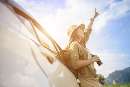 female traveler backpacking on tourist road with sky and mountains in front
