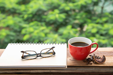 Hot coffee on Red cup on wood table and notebook memory.の写真素材