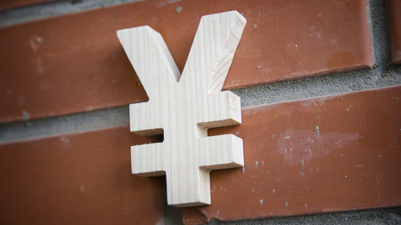 Wooden yen symbol on a brick wall backgroundの写真素材