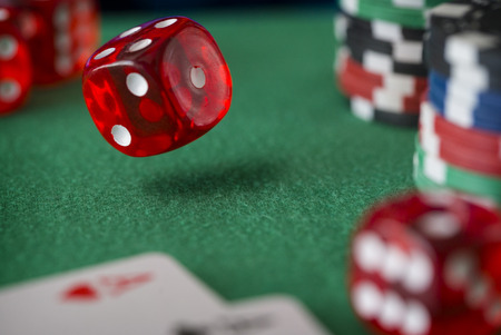 Red casino dice rolls and casino chips on green tableの写真素材