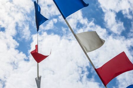 Colorful flags on blue sky with cloudsの写真素材