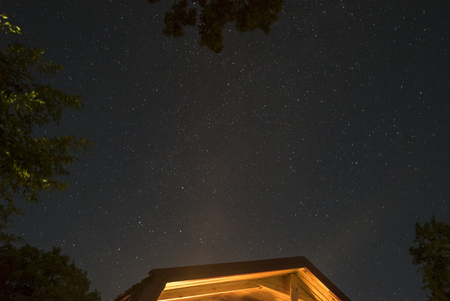 Beautiful night sky over the roof of the house and the oak trees.の写真素材