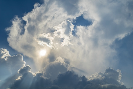 Sun shines through dark storm clouds before rainの写真素材