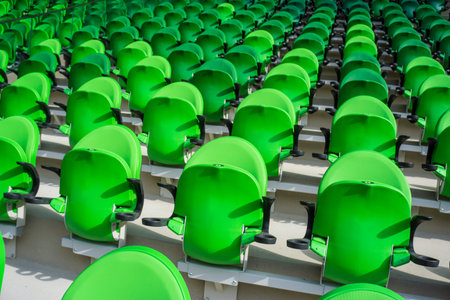 Green seating rows in a stadium with weathered chairsの写真素材