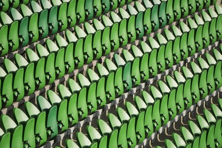 Green seating rows in a stadium with weathered chairsの写真素材