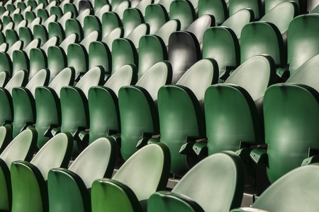 Green and black seating rows in a stadium with weathered chairsの写真素材