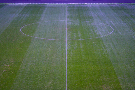 Green artificial grass soccer field with white line and center circle. Winter break.