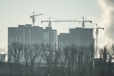 Silhouette building crane and building under construction against the skyの写真素材