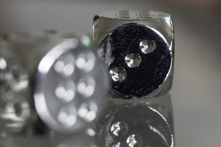 Two metal dices on glass background