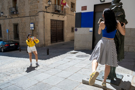 Mexican woman taking photo of her friend. Latin women friend having fun and enjoying the city of Tolero, Spain.の写真素材
