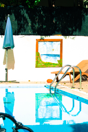 Pool with sun lounger and parasol. Retro style. On the wall hangs a painting. Summer dressesの写真素材