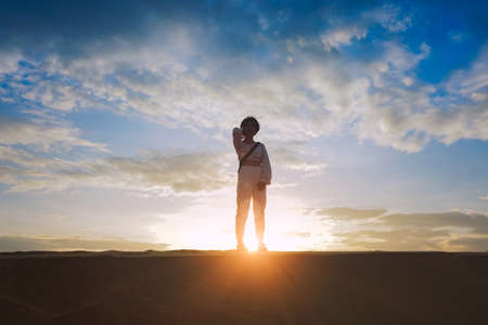 A girl standing in desert, There are the sun and cloud behide hers.の写真素材