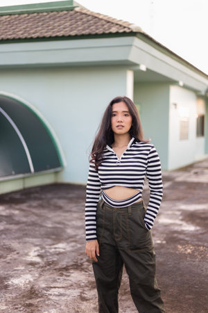 The girl has a skin color of honey or tan. Wearing black and white striped clothes Street photography poses on rooftopの写真素材