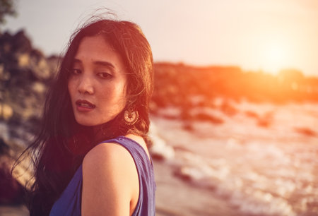 Asian girl wear Indigo dyed cotton on the beach,orange light flare.の写真素材