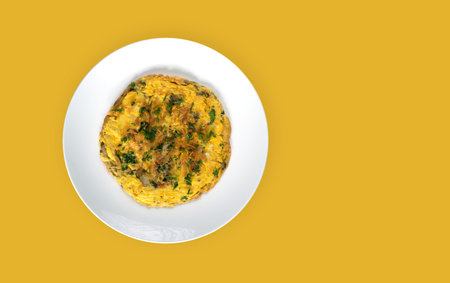 Herbal omelette in a white plate isolated on a yellow background