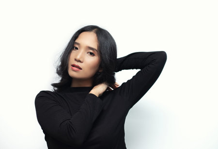 Woman with black curly hair Wearing a black turtleneck sweater Poses shooting on a white backgroundの写真素材