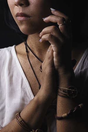 Asian short black haired woman Wearing jewelry made of leather and stone On her face, there is a small freckle On a black background and shadowsの写真素材