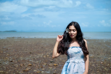 Asian girl wear Indigo dyed cotton long skirt on the beach,blue sky and sea,orange light flare.の写真素材
