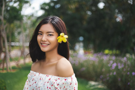 Beautiful asian short hair girl with perfect tan skin smile happily She used the yellow flowers to tuck at her ear,  The beautiful face of a Thai woman.の写真素材