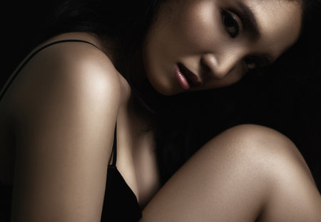 beautiful young woman closeup face and glossy skin under glamour low key conceptの写真素材