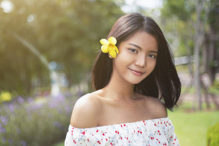 Beautiful asian short hair girl with perfect tan skin smile happily She used the yellow flowers to tuck at her ear,  The beautiful face of a Thai woman.の写真素材