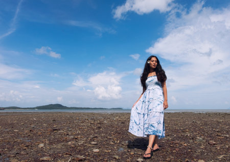 Asian girl wear Indigo dyed cotton long skirt on the beach,blue sky and sea,orange light flare.の写真素材