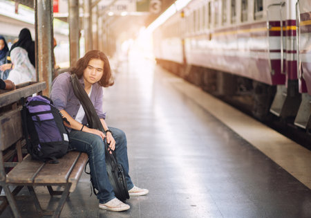 Long haired man that looks cool He is a traveler or nomadic musician who is backpacking and guitars, walking near train track in rural.の写真素材