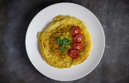 Omelette with tomatoes slide, coriander and scallion. top view. isolated on white dish with grey cement background.の写真素材