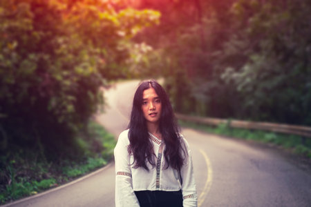 The girl is on the jungle way in the autumn with orange sunshineの写真素材
