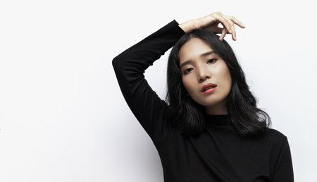 Woman with black curly hair Wearing a black turtleneck sweater Poses shooting on a white backgroundの写真素材