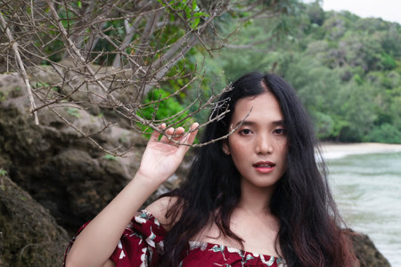 The girl is pulling the branches to close the face on the beach.の写真素材