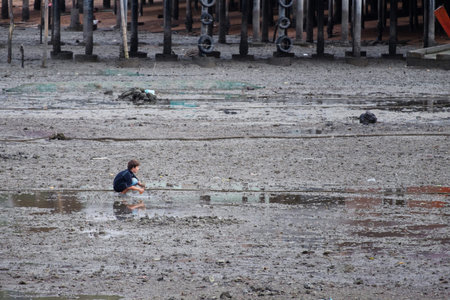 KRABI,THAILAND-AUGUST 18, 2018 : The boy is looking for something on the beach filled with...