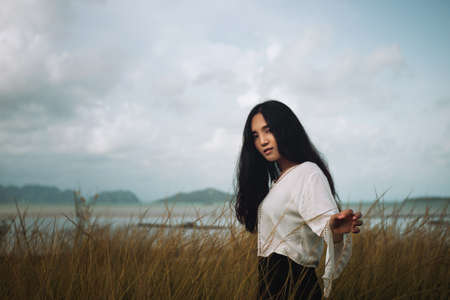 Asian long hair girl in white clothes enjoys life in nature coastal field.の写真素材