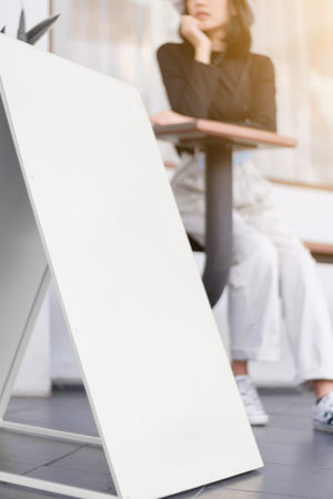 Vertical white signage front store with a blurred woman, Perspective view.の写真素材