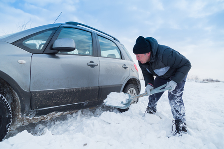 Man shoveling snow to free his stuck carの写真素材