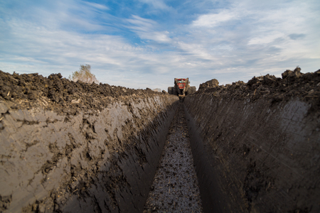 Tractor with double wheeled ditcher digging drainage canalの写真素材