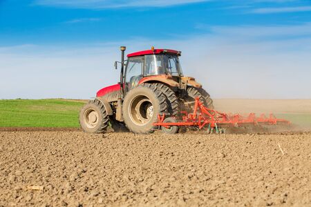 Tractor cultivating field at springの写真素材