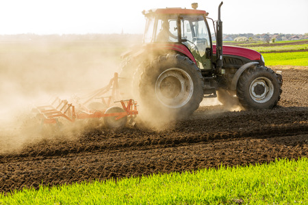 Farmer in tractor preparing land with seedbed cultivatorの写真素材