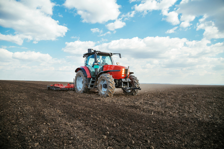 Farmer in tractor preparing land with seedbed cultivatorの写真素材