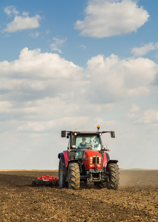 Farmer in tractor preparing land with seedbed cultivatorの写真素材