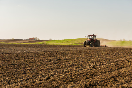 Farmer in tractor preparing land with seedbed cultivatorの写真素材