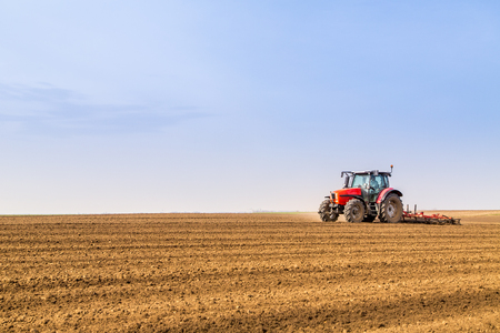 Farmer in tractor preparing land with seedbed cultivatorの写真素材