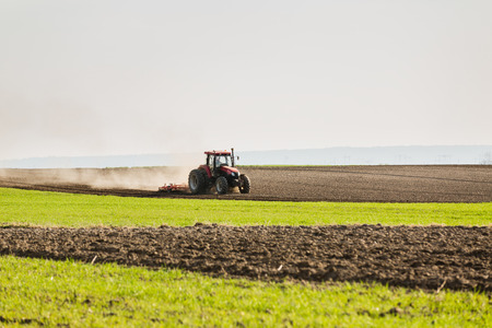 Farmer in tractor preparing land with seedbed cultivatorの写真素材